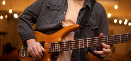 A young guy with a beard plays a bass guitar with five stringsの写真素材