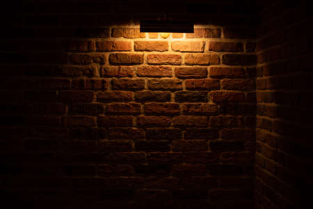 Brick wall illuminated by warm light from a lampの写真素材