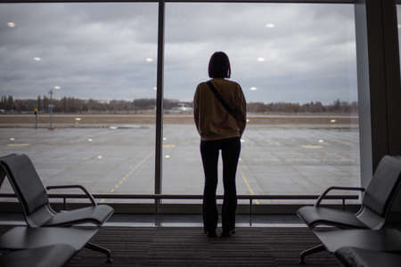 A girl stands in front of a large stained glass window at the airportの写真素材