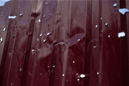 Fence near the house with bullet holes and charapnels after gunshots and fighting during the...