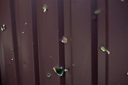 Fence near the house with bullet holes and charapnels after gunshots and fighting during the invasion of Russian troops into Ukraineの写真素材