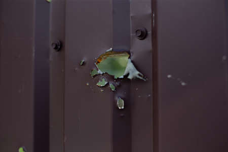 Fence near the house with bullet holes and charapnels after gunshots and fighting during the invasion of Russian troops into Ukraineの写真素材