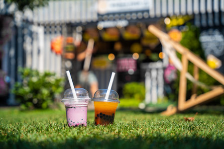 A lone cup of pink bubble tea with a straw, set against a blurred background of a vibrant street food stall.の写真素材