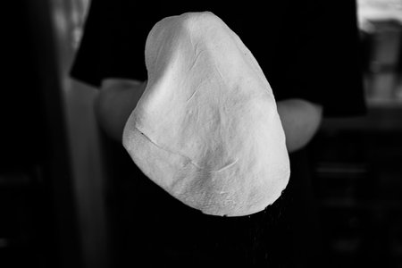 A chef stretches fresh pizza dough, captured in monochrome detail.の写真素材