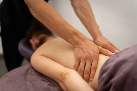A professional masseuse concentrates on massaging the back of a client, focusing on areas of tension to provide therapeutic relief.の写真素材