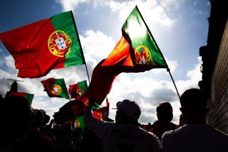 A group of enthusiastic fans waving Portuguese flags at an outdoor event, showcasing national pride...