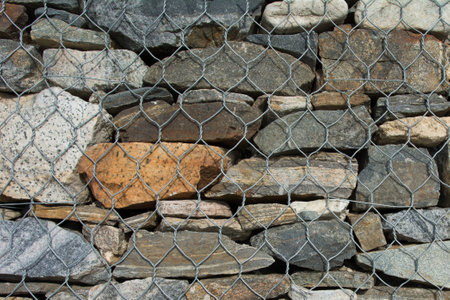 texture background colorful natural stones. Background from natural stones closed with a metal mesh.の写真素材
