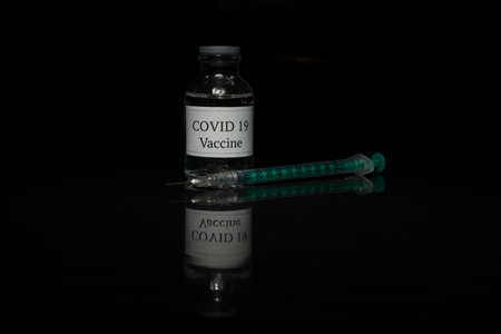 Covid 19 vaccine and syringe on black background