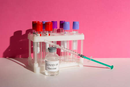 Covid 19 vaccine and syringe on a pink backgroundの写真素材