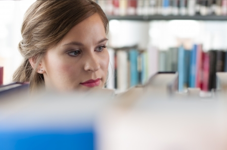 Portrait of female student selecting a bookの写真素材
