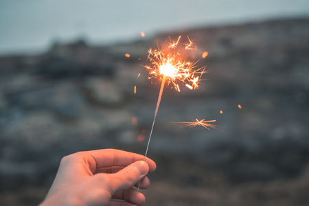Hand holding a lit sparkleの写真素材