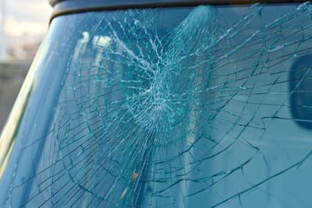 Broken windshield window on a car after getting smashed with a rock.
