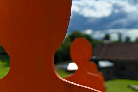 Orange wooden silhouettes of people standing in a line.の写真素材
