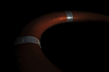 Orange round life buoy with reflectors isolated on black background.の写真素材
