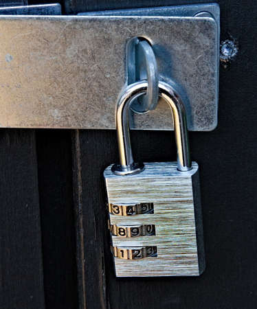 A modern padlock with numerical dials locking a black door. Close-up . High quality photoの写真素材