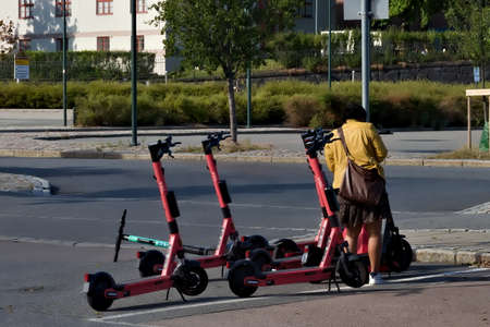 Oslo, Norway - Aug. 29th 2020: Woman renting electric kick bike by rental station in the city.
