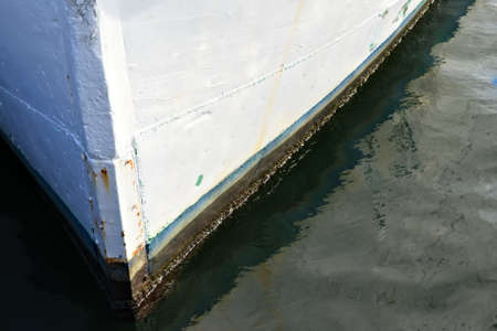 Bow of white wooden boat sitting on its moorings on the dock.の写真素材