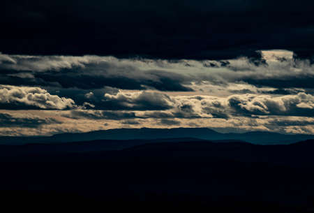 Dark gloomy evening panoramic view over dense woods and mountains in the distance. High quality...