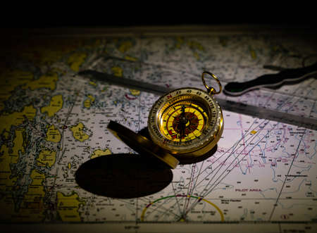 Antique golden compass and old ocean chars in a low lit vintage look. High quality photo