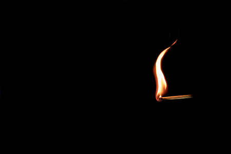 Single match stick burning a clean orange flame. Isolated on black background. . High quality photoの写真素材