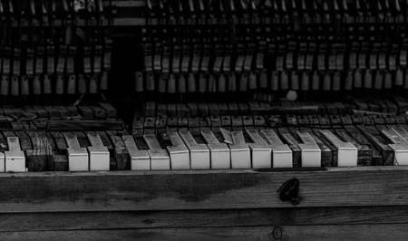 Close up black and white image of an abandoned wrecked piano sitting outdoors. . High quality photo