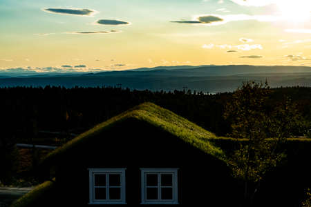 Old cabin with turf roof overseeing a beautiful wilderness valley at sunset. . High quality photo