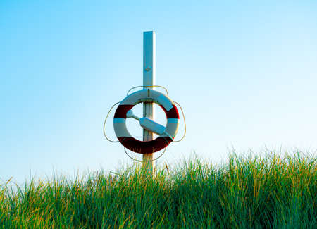 Round life saving buoy hanging ready on a pole by the beach. . High quality photo
