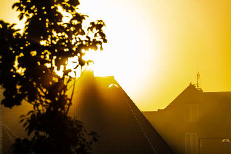 The first rays of light from the sun breaks through the morning mist over the city roof tops. . High quality photoの写真素材