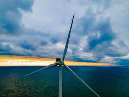 Modern wind turbine by the sea at sunset generating clean energy. . High quality photo
