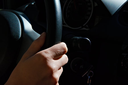 Female hand on a black steering wheel of a car while driving. Close up. . High quality photoの写真素材
