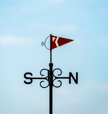 Wind vane with a small flag and north and south indicators. Made from cast iron painted black. . High quality photoの写真素材