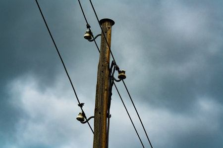 Old wooden post with power and phone lines on porcelain holders.の写真素材