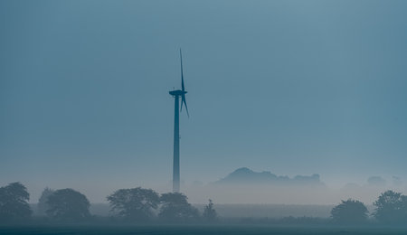 Wind turbine in morning haze at sunrise over the fields. . High quality photoの写真素材