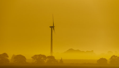 Wind turbine in morning haze at sunrise over the fields. . High quality photoの写真素材