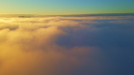 Flying above white clouds with orange sunlight and clear blue sky. High quality photo
