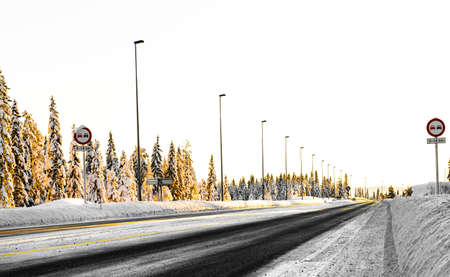 Icy winter road running through a snow covered forest landscape. . High quality photoのeditorial素材