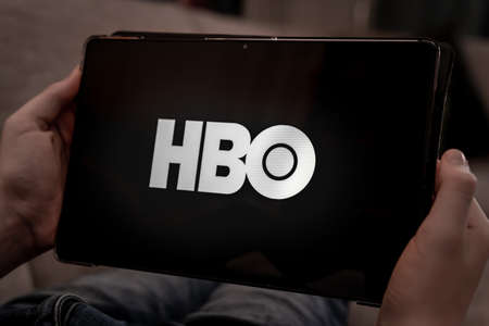 Hands holding tablet with HBO logo on a black screen. Shallow depth of field. High quality photoのeditorial素材