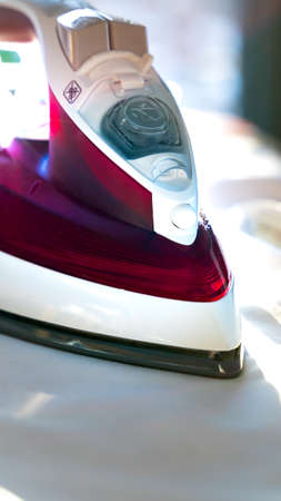 Close up of a steam iron on an ironing board. Blurred background. High quality photoの写真素材