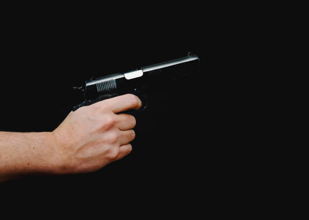 Hand holding a gun, isolated on black background. High quality photo