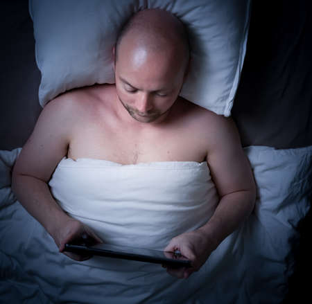 Man lying in bed, stressed can't sleep staring at the ceiling. High quality photoの写真素材