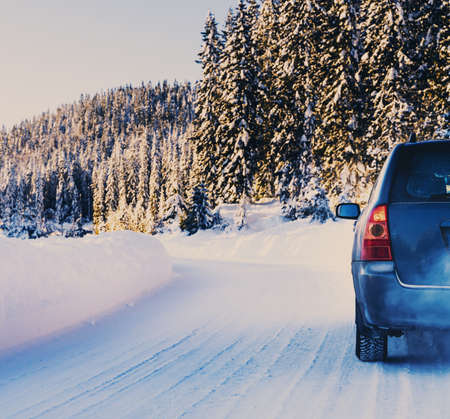 Car driving on a snow covered road in a wilderness forest on a bright sunny winters day. High quality photoの写真素材