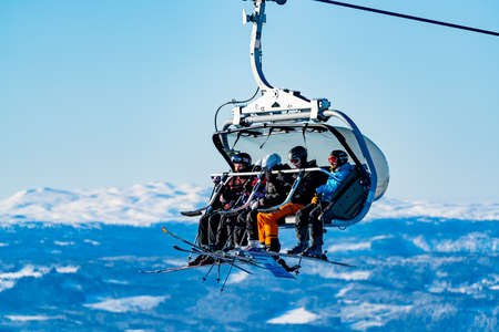 Panoramic view over a ski resort with people in chair lifts and majestic mountains in the background. High quality photoのeditorial素材