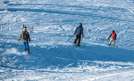 Group of downhill skiers on a slope at a ski resort on a bright sunny day. High quality photoの写真素材