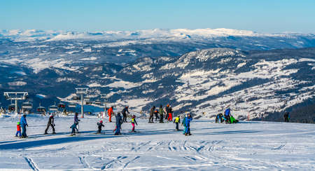Panoramic view over a ski resort with people in chair lifts and majestic mountains in the background. High quality photoのeditorial素材