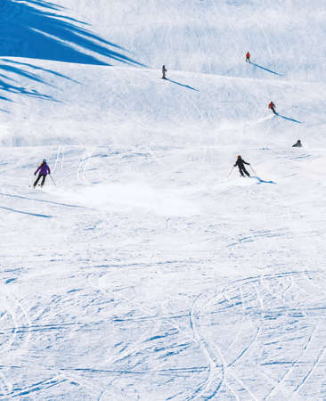 Skiers riding down a slope on a sunny day at a ski resort. High quality photo
