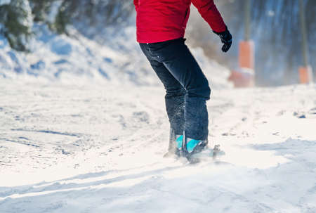 Close up of a snowboarders legs while speeding down a steep slope in the evening light. Shallow depth of field. High quality photoの写真素材