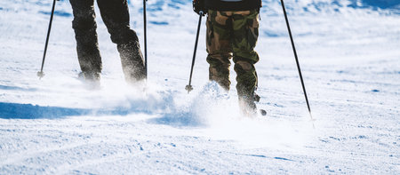 Close up of skiers legs on the slope at a winter ski resort. In bright morning sunlight. Shallow depth of field. High quality photoの写真素材