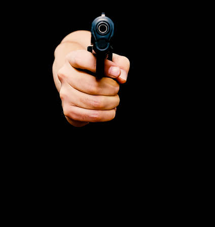 Hand aiming a loaded gun at the camera, isolated on black with shallow depth of field.の写真素材