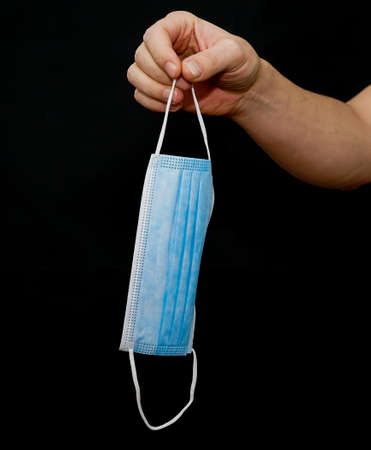 Hand holding a used surgical face mask. Isolated on black.の写真素材