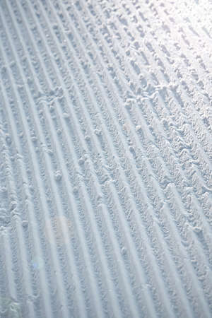 Close up of groomed tracks on a slope in a downhill ski resort on a sunny day. Shallow depth of field.の写真素材